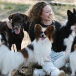 Cheerful female with obedient dogs relaxing in countryside