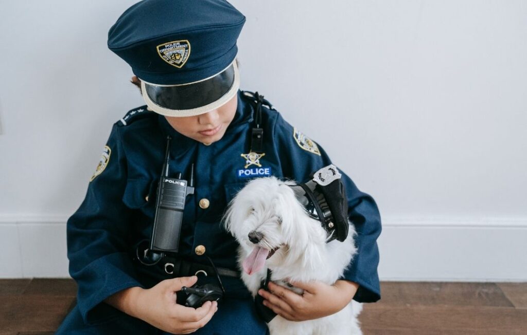 Boy Wearing Police Costume Holding a Dog