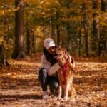 woman kneeling with dog in the woods