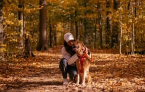 woman kneeling with dog in the woods