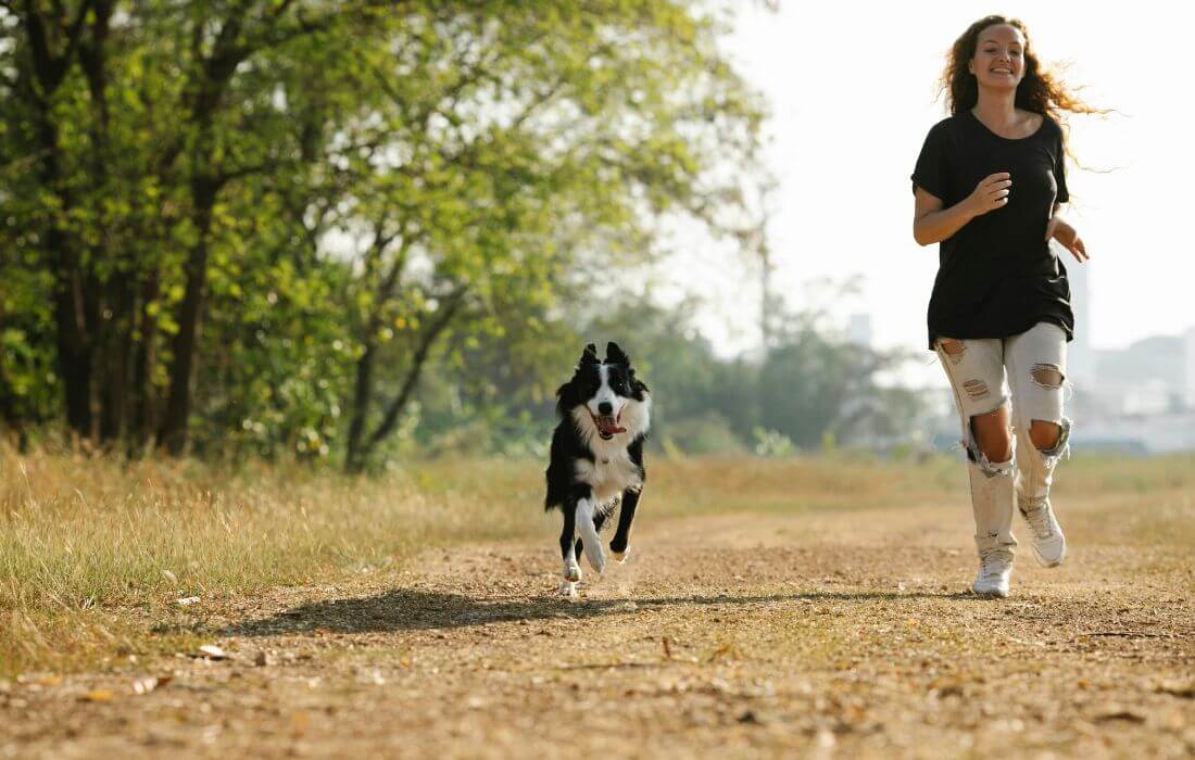 woman with dog running in countryside