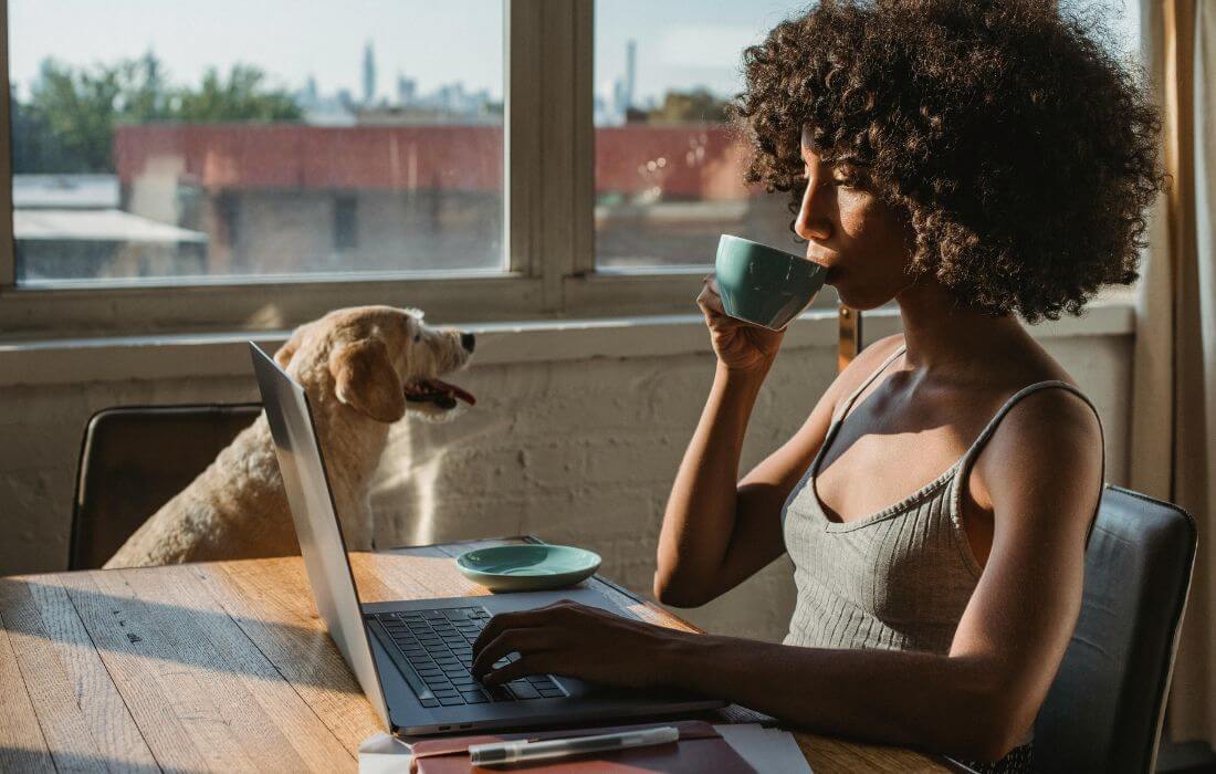 using laptop and drinking coffee near dog