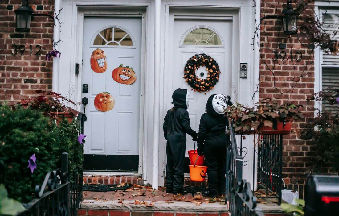 Anonymous kids in skeleton costumes playing trick or treat