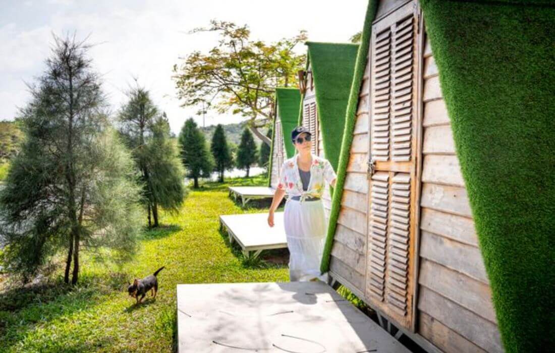 Woman with dog walking by unique countryside cabins in sunny outdoor setting